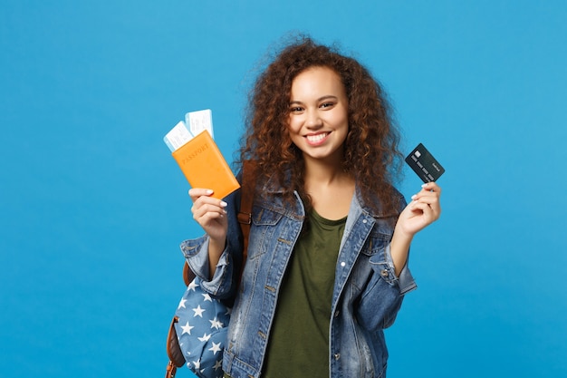 Jeune étudiante adolescente afro-américaine en vêtements en jean, passe de maintien de sac à dos isolé sur mur bleu