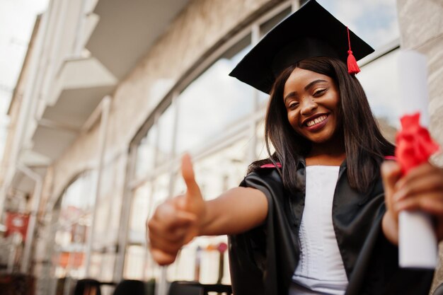 Photo jeune étudiante afro-américaine avec diplôme pose à l'extérieur.