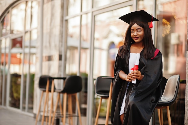 Jeune étudiante afro-américaine avec diplôme pose à l'extérieurxA