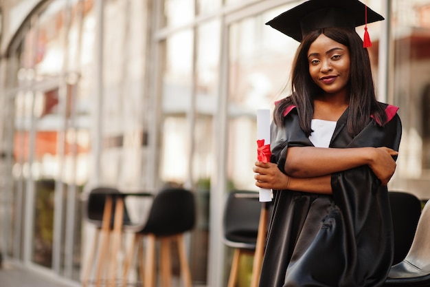 Jeune étudiante afro-américaine avec diplôme pose à l'extérieurxA