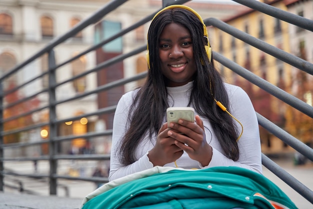 Jeune étudiante afro-américaine écoutant de la musique avec son téléphone intelligent