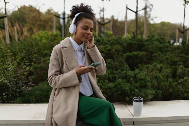 Jeune étudiante américaine écoutant de la musique avec des écouteurs et regardant un téléphone portable avec un