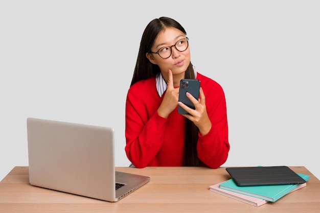 Jeune étudiante asiatique sur un lieu de travail avec un ordinateur portable isolé