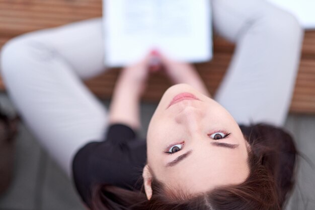 Une jeune étudiante asiatique lit un livre de cours Préparation de la session et des examens Portrait de ville en plein air