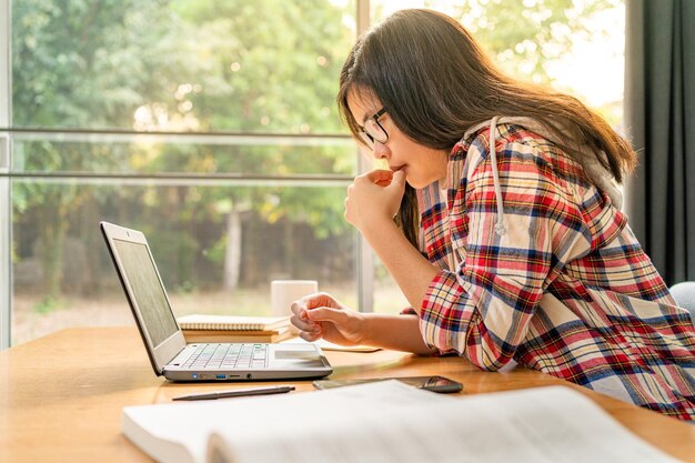 Jeune étudiante asiatique travaillant et étudiant en ligne à domicile en utilisant l'apprentissage à distance