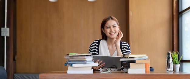 Jeune étudiante asiatique travaillant sur tablette numérique dans la bibliothèque