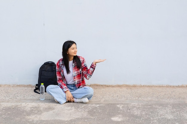 Une jeune étudiante assise sur le sol avec un sac à dos à l'école