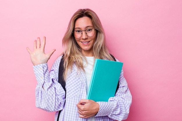 Jeune étudiante australienne isolée sur fond rose souriant joyeux montrant le numéro cinq avec les doigts.