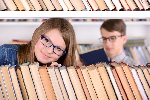 Jeune étudiante avec bibliothèque de sélection de livre