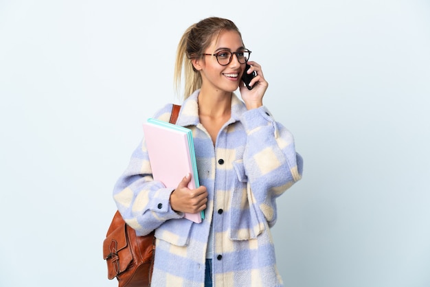 Jeune étudiante sur blanc en gardant une conversation avec le téléphone mobile