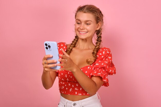 Jeune étudiante caucasienne de beauté joyeuse avec téléphone dans les mains se tient en studio