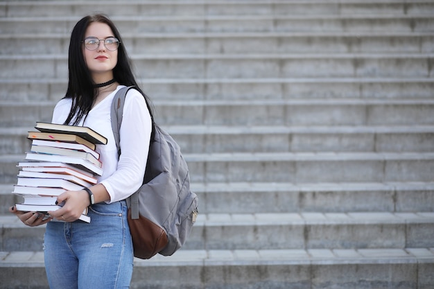 Jeune étudiante dans la rue avec un sac à dos et des livres