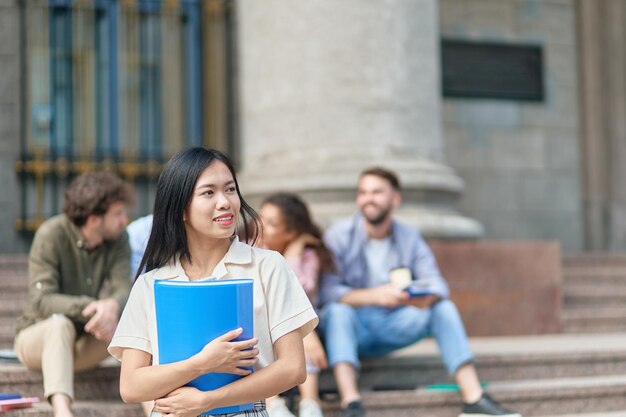 Jeune étudiante debout devant le bâtiment de l'université