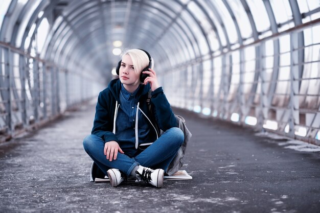 Jeune étudiante écoutant de la musique dans de gros écouteurs dans le tunnel du métro