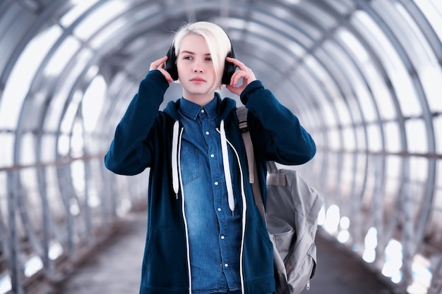 Jeune étudiante écoutant de la musique dans de gros écouteurs dans le tunnel du métro