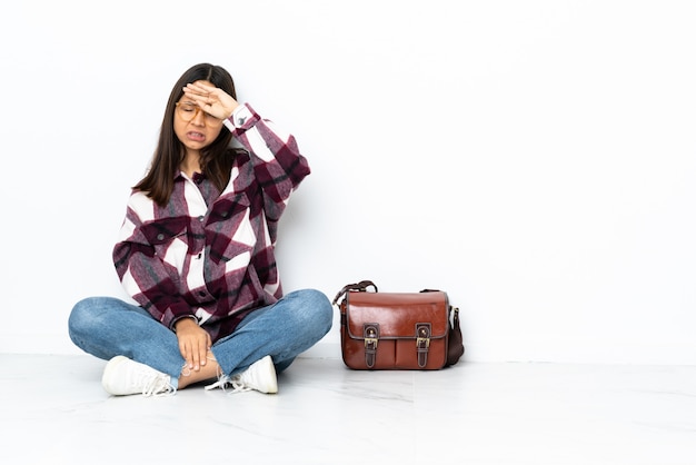 Jeune étudiante femme assise sur le sol avec une expression fatiguée et malade