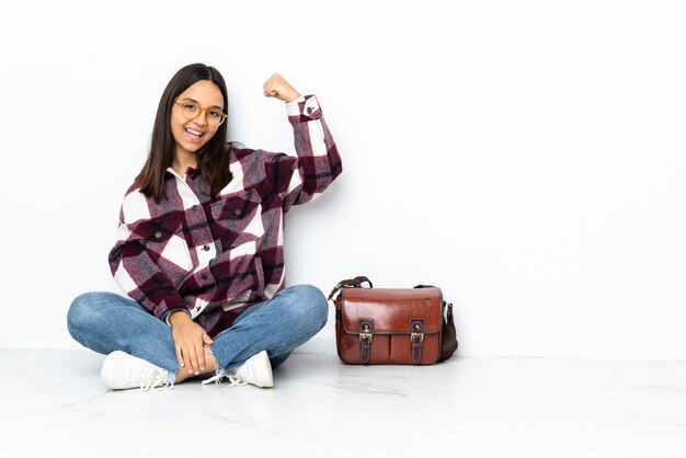 Jeune étudiante femme assise sur le sol faisant un geste fort