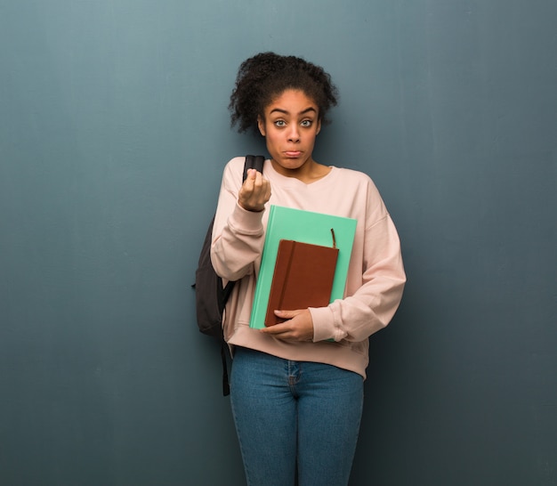 Jeune étudiante femme noire faisant un geste de besoin.