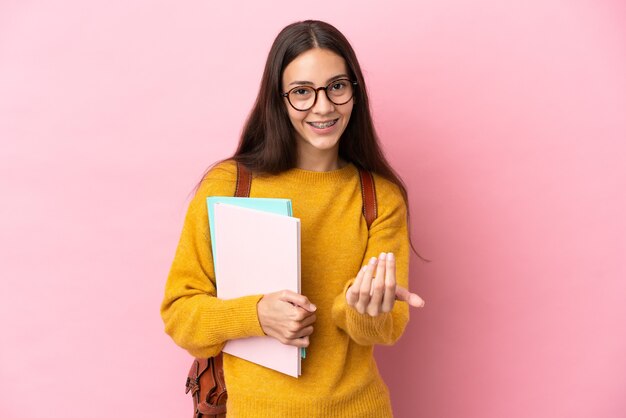 Jeune étudiante sur fond isolé invitant à venir avec la main. Heureux que tu sois venu