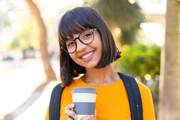 Jeune étudiante gagne un parc avec une expression heureuse