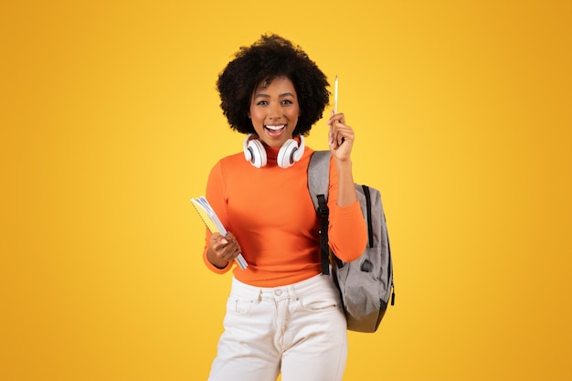 Une jeune étudiante heureuse avec un afro et des écouteurs autour du cou.