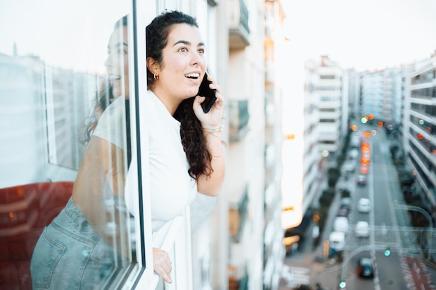 Jeune étudiante indépendante vérifiant son téléphone tout en travaillant à la maison et recevant des appels de nouvelles surprises et préparant sa journée. Concept de travail à distance à domicile