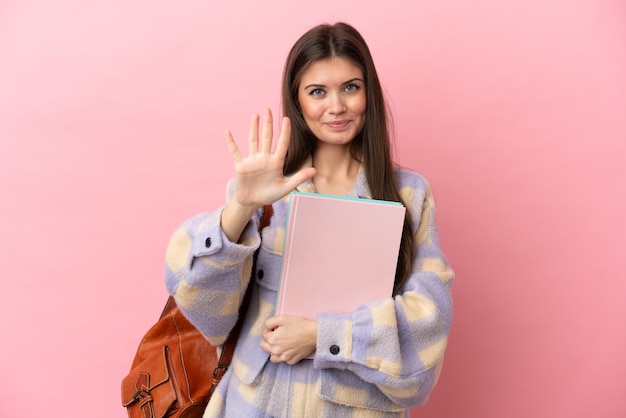 Jeune étudiante isolée sur fond rose comptant cinq avec les doigts