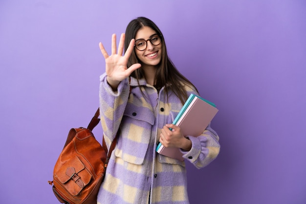 Jeune étudiante isolée sur fond violet comptant cinq avec les doigts