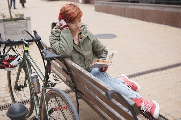 Jeune étudiante lisant un livre, se détendre après avoir fait du vélo dans la ville