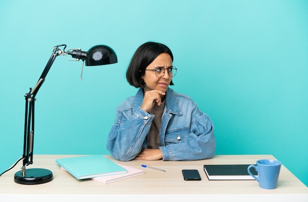 Jeune étudiante métisse femme étudiant sur une table ayant des doutes et pensant