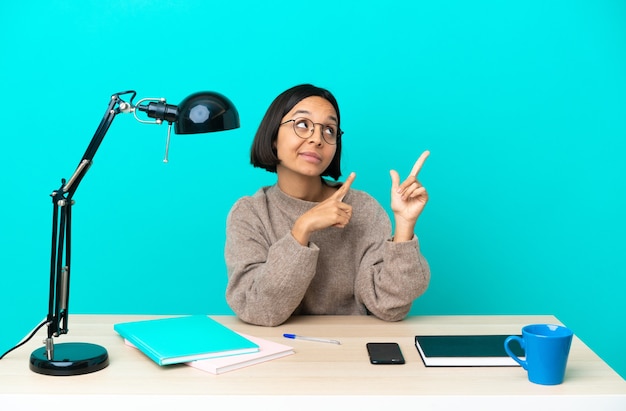 Jeune étudiante métisse femme étudiant sur une table pointant avec l'index une excellente idée