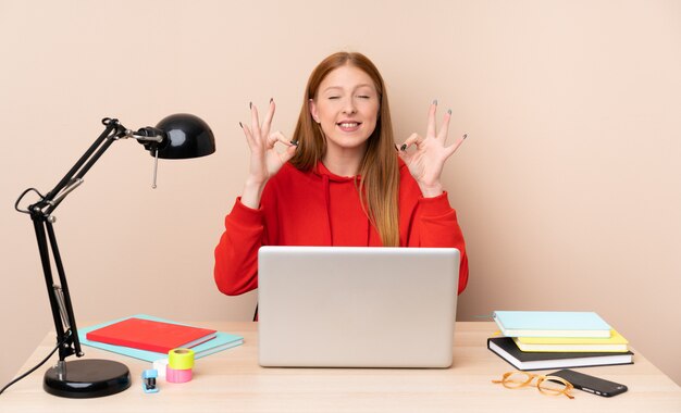 Jeune étudiante en milieu de travail avec un ordinateur portable dans une pose zen