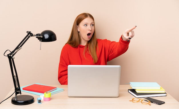 Jeune étudiante en milieu de travail avec un ordinateur portable pointant loin