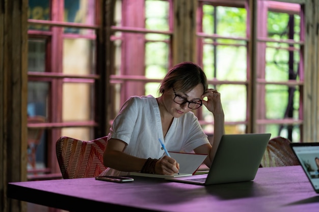 Jeune étudiante pensive concentrée assise avec un ordinateur portable femme caucasienne travaillant dans un espace de coworking