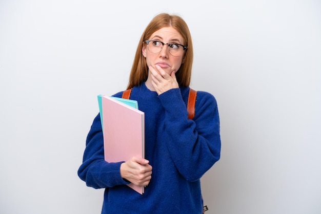 Jeune étudiante rousse femme isolée sur fond blanc ayant des doutes