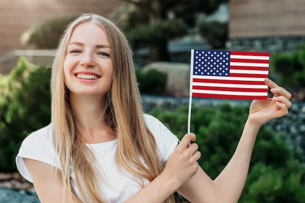 Jeune étudiante souriante et montre un petit drapeau américain et se dresse dans le contexte de l'université