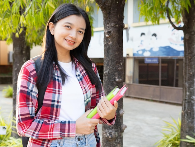 Une jeune étudiante tient un sein et marche à l'école.