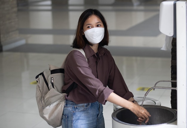 Jeune étudiante universitaire portant un masque et se lavant les mains pendant covid19