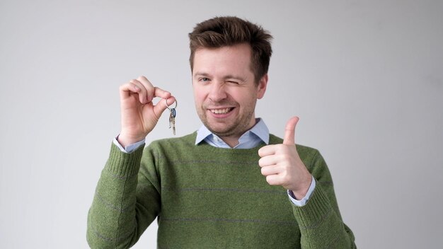 Un jeune européen montre les clés de son nouvel appartement, il est heureux d'avoir acheté sa propre maison