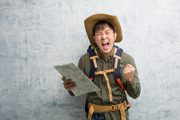 Jeune explorateur chinois tenant une carte surprise et choquée