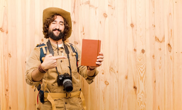 Photo jeune explorateur fou avec chapeau de paille et sac à dos sur fond de bois