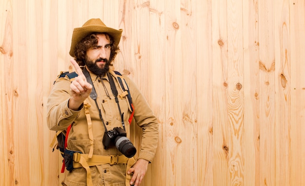 Jeune explorateur fou avec chapeau de paille et sac à dos sur mur en bois