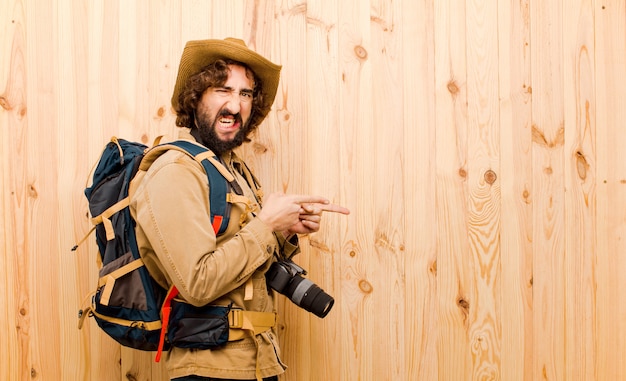 Jeune explorateur fou avec chapeau de paille et sac à dos sur mur en bois