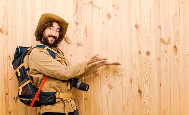 Jeune explorateur fou avec chapeau de paille et sac à dos sur mur en bois