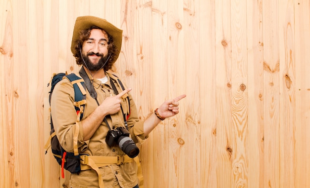 Jeune explorateur fou avec chapeau de paille et sac à dos sur mur en bois