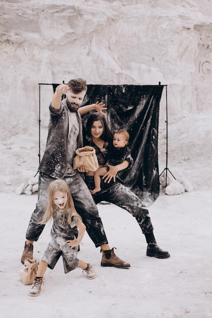 Jeune famille avec 2 enfants vêtus de vêtements noirs posant pour une photo lors d'une séance photo stylisée dans un endroit blanc naturel amusant, élégant et charismatique Famille avec deux filles