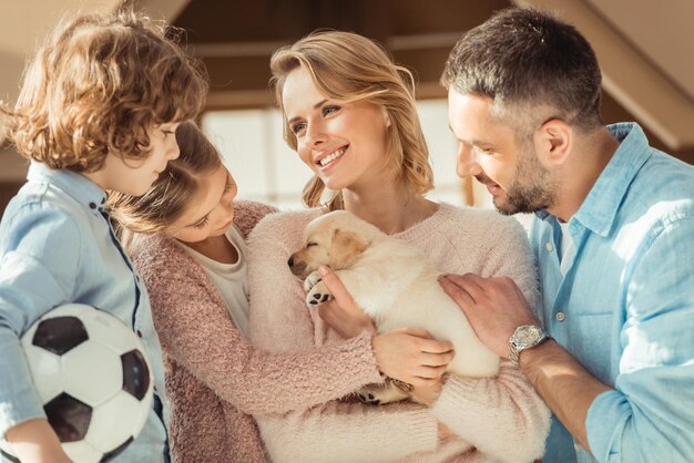 jeune famille avec un adorable chiot labrador devant une maison en carton