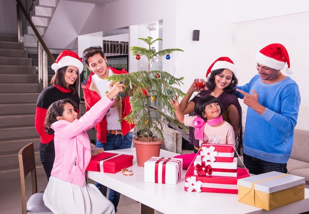 Jeune famille asiatique indienne célébrant Noël avec un cadeau tout en portant un chapeau de père Noël