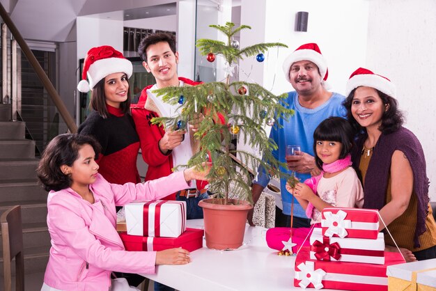 Jeune famille asiatique indienne célébrant Noël avec un cadeau tout en portant un chapeau de père Noël