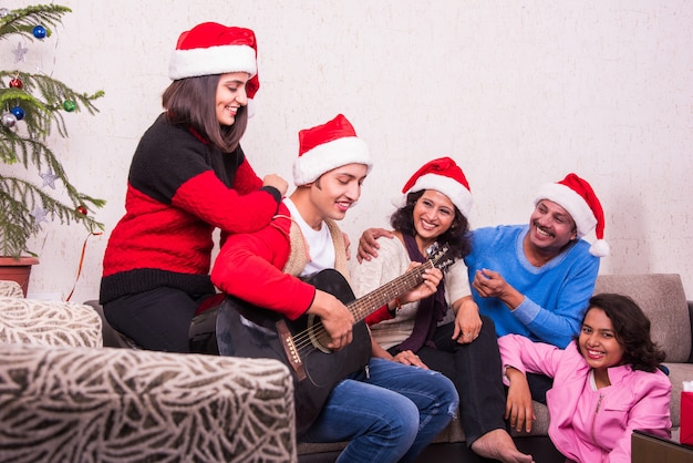 Jeune famille asiatique indienne célébrant Noël avec un cadeau tout en portant un chapeau de père Noël